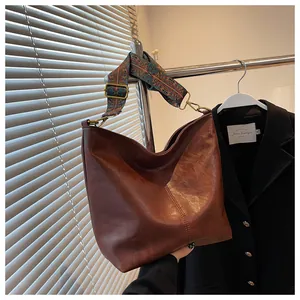 Detailed close-up of dark brown leather hobo bag with ethnic style jacquard strap