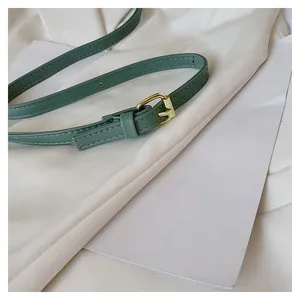 Detailed close-up of sage green faux leather belt with elegant gold metal buckle