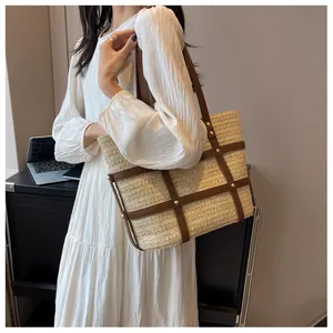Detail of beige straw tote with brown leather straps and gold rivets on white dress