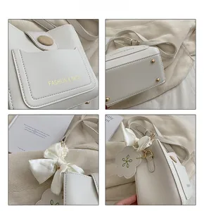 Détails du sac seau en cuir crème avec clous dorés et breloque ruban élégante