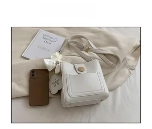 Détail du sac seau blanc avec boucle en bois et accessoire nœud en soie