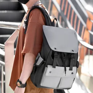 Side view of a grey and black nylon laptop backpack with buckle flap and side pockets