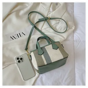 Detail of striped canvas bucket bag with adjustable green strap and gold metal hardware