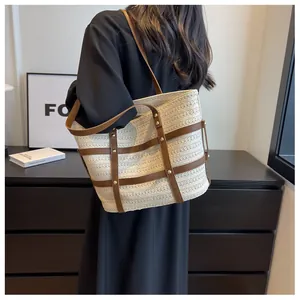 Straw tote bag detail with cream weave and brown leather straps worn by a model