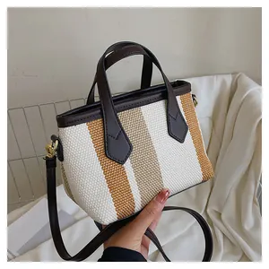 Detail of striped canvas bucket bag showing woven texture and brown leather straps