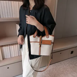 Vintage canvas bucket bag with brown leather trim and metal lock shown in a lifestyle setting