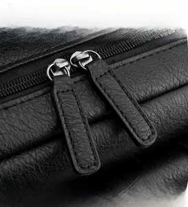 Close-up detail of smooth dual metal zippers on black lychee pattern leather backpack
