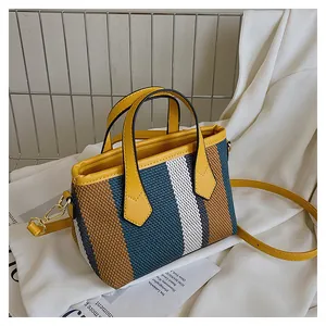 Macro shot of striped woven canvas bucket bag showing colorful fabric texture and yellow handle