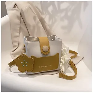 Sac seau bicolore blanc et jaune avec boucle en bois et charme de fleur sur chaise blanche