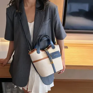 Retro canvas and navy leather bucket bag with top handles and adjustable shoulder strap