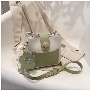 Sac seau minimaliste blanc et vert avec boucle en bois et foulard sur une chaise blanche