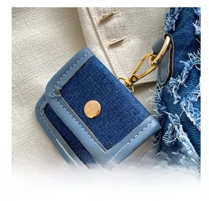 Close-up of denim fabric texture with light blue leather trim and gold metal clasp
