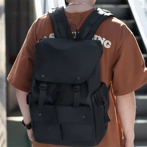 Detail of black nylon backpack featuring dual buckle flap and ergonomic shoulder straps