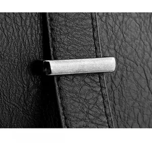 Detail of black textured leather backpack with a brushed silver metal decorative piece