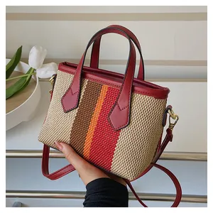 Detail of color-block woven bucket bag featuring red leather trim and gold hardware