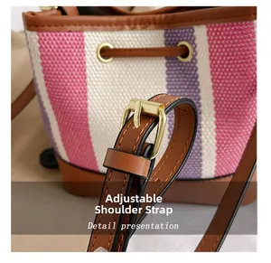 Close-up of adjustable brown leather shoulder strap with gold buckle on striped bucket bag