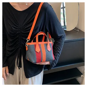 Fashionable striped canvas crossbody bag with orange handles and adjustable strap