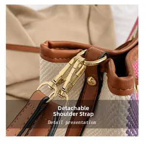 Detail of the detachable shoulder strap with golden hardware on a canvas bucket bag