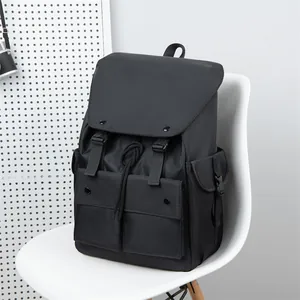 Detail view of the black nylon backpack showing the front pockets and flap cover design