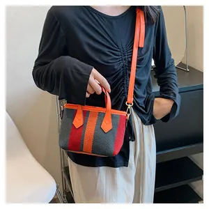 Detail of striped knitted crossbody bag with orange leather handles and shoulder strap
