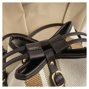 Macro shot of striped woven bucket bag featuring premium leather drawstring and gold hardware