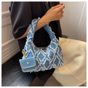 Detail of light blue washed denim tote bag featuring frayed diamond quilted stitching