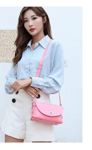 Detail of pink leather crossbody bag with metal twist lock and silver rivet trim on model