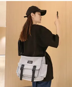 Détail de la sacoche gris clair avec boucles noires et design technique à bandoulière