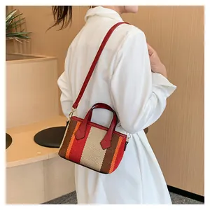 Detail of colorful striped woven canvas mini bag with red leather straps and gold hardware