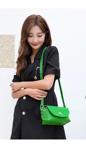 Detail of bright green mini crossbody bag with silver twist lock and rivet accents