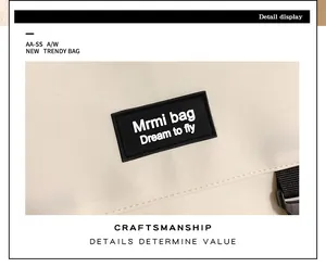 Détail de l'étiquette de marque noire sur un sac à bandoulière blanc crème