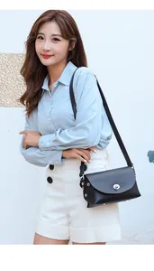Side view of a black leather crossbody bag with metal lock on a model with blue shirt