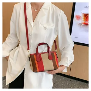 Detail of multi-color striped canvas bag with red leather handles and strap on model