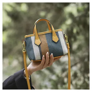 Detailed shot of yellow leather handles on a striped woven mini bucket bag for women