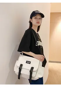 Détail d'un sac messager en toile blanche avec boucles noires et poche latérale