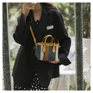 Close-up of a striped fabric mini bucket bag with yellow leather handles and shoulder strap