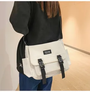 Détail du sac à bandoulière blanc avec boucles noires et poche latérale au style épuré