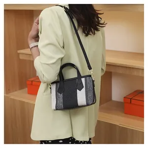 Detailed back view of a striped canvas bucket bag worn by a model in a warm setting