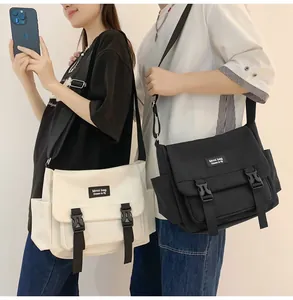 Détail de sacs bandoulière noir et beige avec boucles et étiquettes de marque tissées