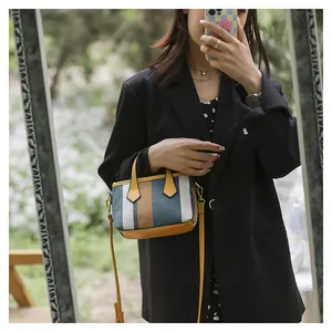 Close-up of a striped canvas bucket bag with yellow leather handles and golden hardware