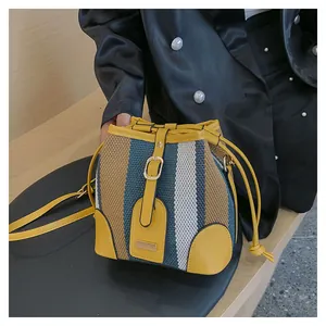 Detail of striped bucket bag featuring yellow leather trim and woven contrast fabric