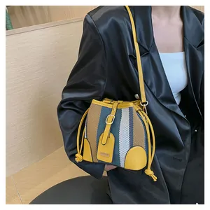 Detail of striped contrast bucket bag with woven texture and yellow faux leather trim