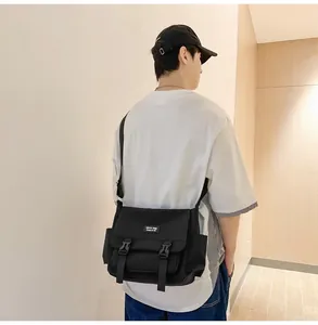 Détail d'un sac messager en toile noire avec boucles doubles et poche latérale pratique