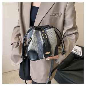 Detail of striped tweed bucket bag with leather trim on model wearing a brown blazer