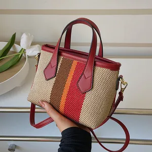 Chic striped woven bucket bag with red leather handles and adjustable shoulder strap