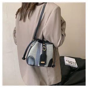 Close-up of striped bucket bag with black leather trim and elegant gold hardware details