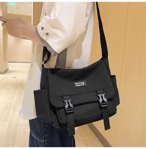 Détail du sac messager en toile noire avec boucles en plastique et bandoulière réglable