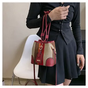 Detail of striped bucket bag with coarse woven texture and red leather accents