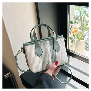 Minibolso bandolera de lona a rayas con ribete de cuero verde y herrajes dorados