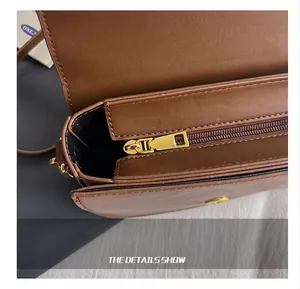 Close-up of smooth gold metal zipper and stitching detail on brown leather shoulder bag